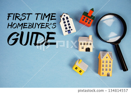 First-Time Homebuyer's Guide text with house models and magnifying glass on blue background 134814557
