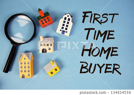 First Time Home Buyer text with house models and magnifying glass on blue background First Time Home Buyer text with house models and magnifying glass on blue background 134814559