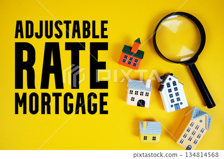 ARM Adjustable-Rate Mortgage text with house models and magnifying glass on yellow background 134814568