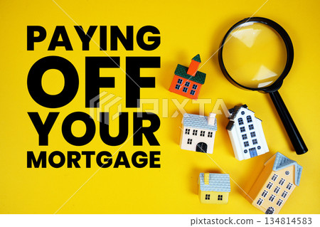 Paying Off Your Mortgage text with house models and magnifying glass on yellow background 134814583