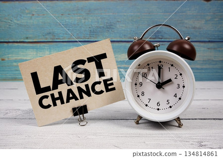 Last Chance text written on paper card with alarm clock on wooden background Last Chance text written on paper card with alarm clock on wooden background 134814861
