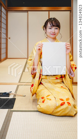 一位身穿和服的年輕女子正在寫書法 一位身穿和服的年輕女子正在寫書法 134814923