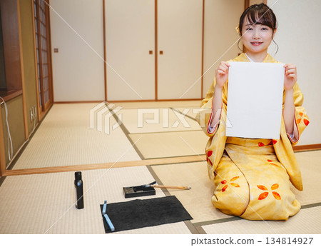 A young woman wearing a kimono writing calligraphy A young woman wearing a kimono writing calligraphy 134814927