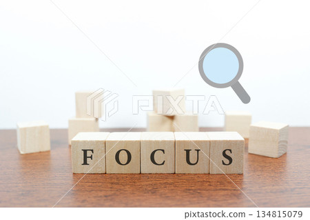 Concept image of concentration with magnifying glass and FOCUS wooden block. 134815079
