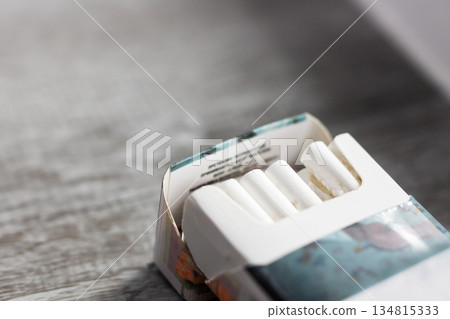 Reflective scene showing unlit cigarette pack illuminated softly in evening ambiance Reflective scene showing unlit cigarette pack illuminated softly in evening ambiance 134815333