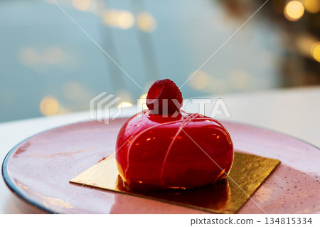 Refined cafe setting showcasing glossy raspberry mousse with reflective light effects Refined cafe setting showcasing glossy raspberry mousse with reflective light effects 134815334