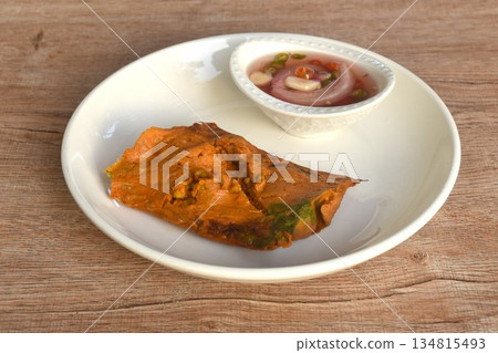 grilled curry fish and egg horseshoe crab wrapped in banana leaf dipping spicy chili sauce grilled curry fish and egg horseshoe crab wrapped in banana leaf dipping spicy chili sauce 134815493