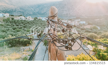 Web of wires on wooden pole with Cretan nature background, old electricity supply system. Web of wires on wooden pole with Cretan nature background, old electricity supply system. 134815515