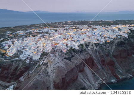 Nightfall view of the famous cliffside architecture of the Greek island Santorini, lights glowing  134815558