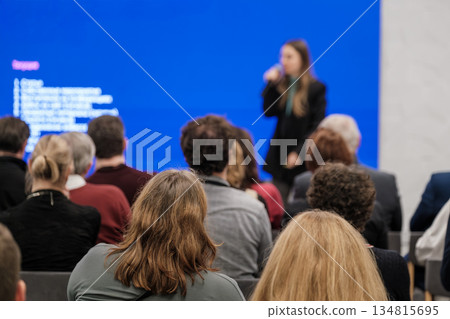 Speaker presents at conference with blue screen to audience in a professional setting Speaker presents at conference with blue screen to audience in a professional setting 134815695
