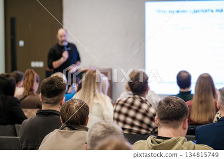 Presenter addresses attentive audience during conference seminar with bright screen in a modern room 134815749