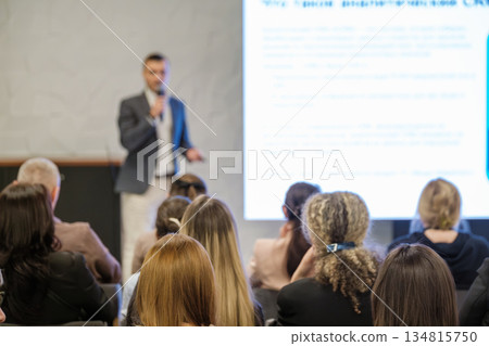 Business presentation in conference room with speaker presenting to attentive audience and large slide 134815750