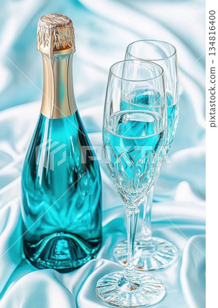 Luxurious turquoise sparkling wine with crystal glasses set on silky white fabric for elegant celebrations 134816400