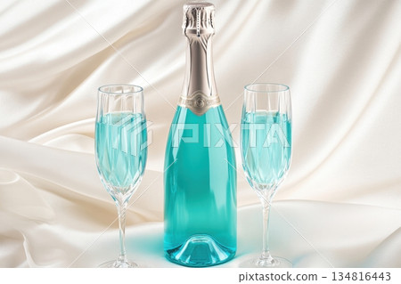 Luxurious turquoise sparkling wine bottle and crystal glasses on white silk backdrop create an elegant setting for celebration 134816443