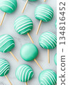Glossy turquoise candy apples with wooden sticks artfully placed on a white marble surface highlighting their glossy finish and playful design 134816452