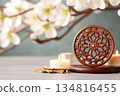 Intricately carved golden Dharma Wheel on an altar surrounded by incense and candles in a tranquil Buddhist setting 134816455