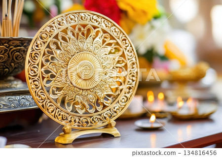 Intricately carved golden Dharma Wheel on an altar surrounded by incense and candles in a serene Buddhist setting Intricately carved golden Dharma Wheel on an altar surrounded by incense and candles in a serene Buddhist setting 134816456