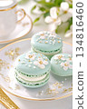Gourmet turquoise macaron with delicate white floral decorations on an elegant porcelain plate in soft lighting 134816460