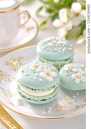 Gourmet turquoise macaron with delicate white floral decorations on an elegant porcelain plate in soft lighting Gourmet turquoise macaron with delicate white floral decorations on an elegant porcelain plate in soft lighting 134816460