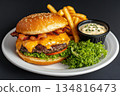 Mouthwatering gourmet cheeseburger with melted cheese, crispy bacon, and fresh lettuce served with fries and dipping sauce on a white plate 134816473