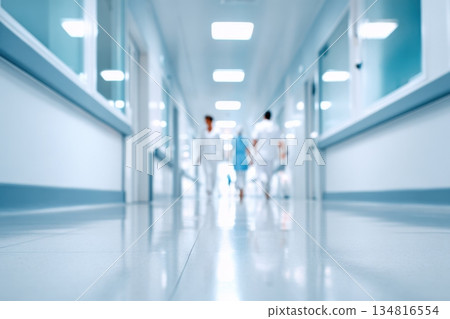 Quiet hospital emergency room corridor with bright lighting, clean floors, and blurred figures of medical staff walking, creating a serene and professional healthcare environment 134816554