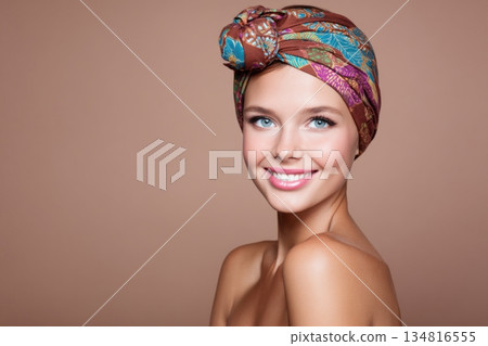 Smiling woman with a colorful headscarf, showcasing a retro beauty portrait, exuding confidence and charm against a soft, neutral background with copy space 134816555