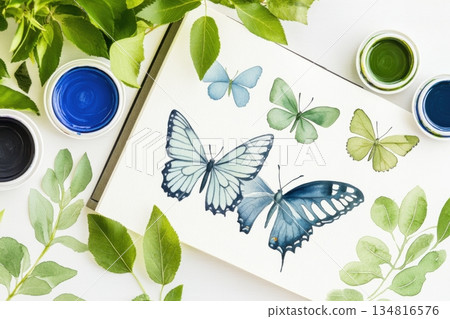 Creative flat lay featuring botanical illustrations, pressed leaves, watercolor paints, and hand-drawn butterflies in a serene workspace 134816576