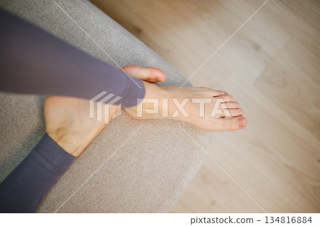 Foot resting on a sofa in a home setting during a daytime Foot resting on a sofa in a home setting during a daytime 134816884