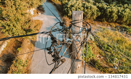 Web of wires on wooden pole with Cretan nature background, old electricity supply system. Web of wires on wooden pole with Cretan nature background, old electricity supply system. 134817431