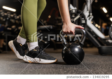 Closeup of woman hand holding kettlebell on gym floor for functional strength training workout 134819295