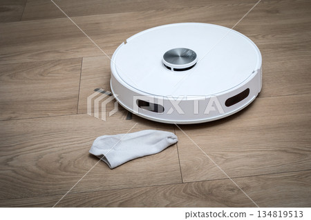 Smart Robotic Vacuum Cleaner Approaching Fabric Obstacle On Modern Wooden Floor Smart Robotic Vacuum Cleaner Approaching Fabric Obstacle On Modern Wooden Floor 134819513