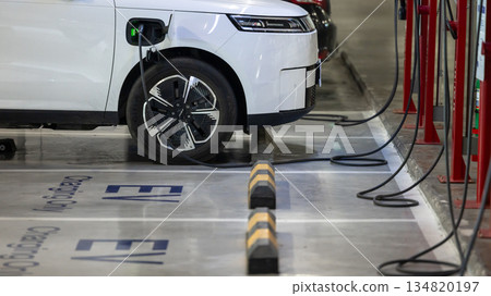 EV charging and electric car, Electric car charging station for charge EV battery, Plug for vehicle with electric engine, EV charger clean energy, Charging point at car parking lot 134820197
