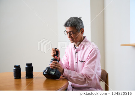 Senior male photographer taking photos as a hobby, camera care and maintenance 134820516