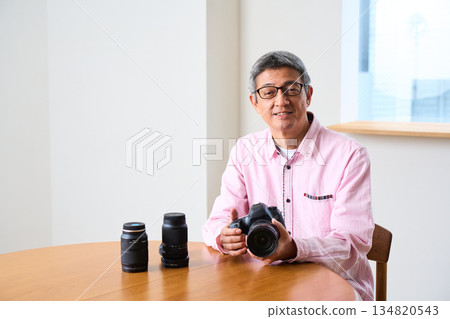 Senior male photographer taking photos as a hobby, camera care and maintenance Senior male photographer taking photos as a hobby, camera care and maintenance 134820543