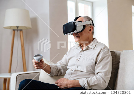 An elderly man wearing modern virtual reality glasses 134820801