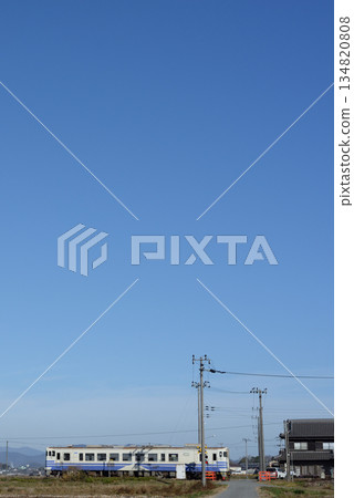 在萬裡無雲的藍天下，一列 Kiha 40 型列車駛過寧靜的鄉村景色。 134820808