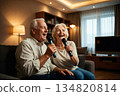Elderly man and woman singing karaoke together in a cozy modern living room 134820814