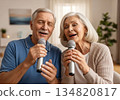 Elderly man and woman singing karaoke together in a cozy modern living room 134820817