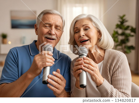 Elderly man and woman singing karaoke together in a cozy modern living room 134820817