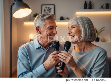 Elderly man and woman singing karaoke together in a cozy modern living room 134820820