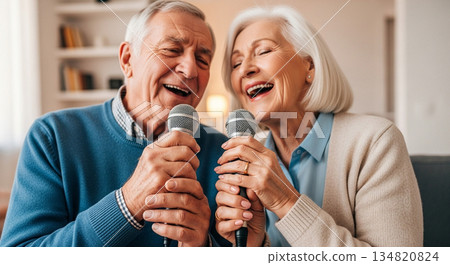 Elderly man and woman singing karaoke together in a cozy modern living room 134820824