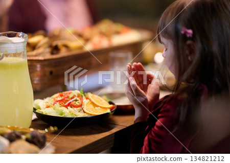 Muslim family shares iftar in a restaurant with Ramadan decorations and warm lighting Muslim family shares iftar in a restaurant with Ramadan decorations and warm lighting 134821212