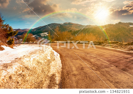 country road winding through winter landscape under blue sky at sunset. mountains in evening light. travel background with snow covered slopes. storytelling cinematic image under the rainbow country road winding through winter landscape under blue sky at sunset. mountains in evening light. travel background with snow covered slopes. storytelling cinematic image under the rainbow 134821931