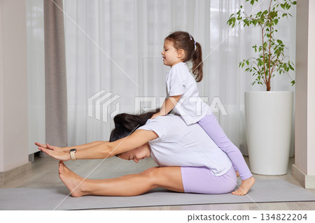 Mother and daughter bonding during a playful yoga session on a mat 134822204