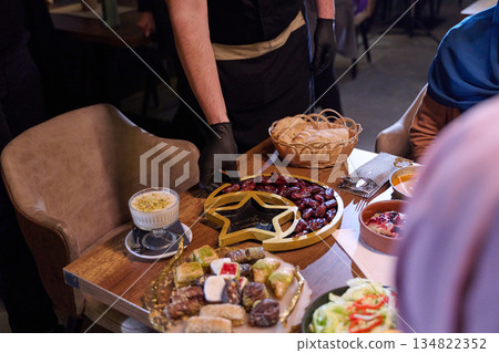 Muslim family shares iftar meal in a warm restaurant setting decorated for Ramadan celebration Muslim family shares iftar meal in a warm restaurant setting decorated for Ramadan celebration 134822352