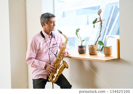 一個男人站在窗邊，手裡拿著薩克斯風 134825100