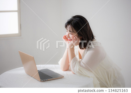 A young cute woman looking at a laptop. Relaxed, happy, fun. Spring pink image of qualifications, studying, etc. A young cute woman looking at a laptop. Relaxed, happy, fun. Spring pink image of qualifications, studying, etc. 134825163
