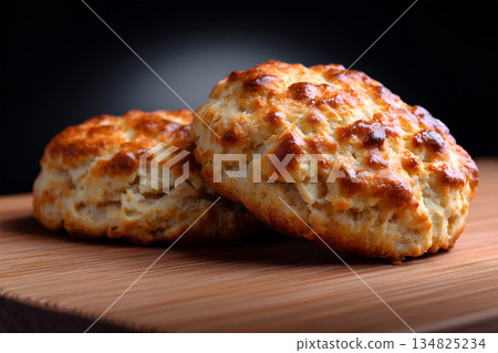 Freshly baked golden biscuits on a wooden surface with a dark background highlighting texture 134825234