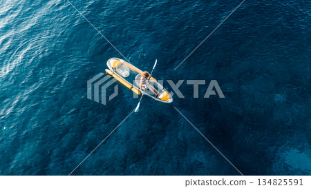Woman swims on kayak in summer blue sea. Drone view, top down 134825591