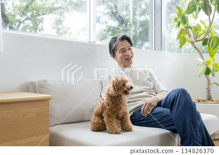 A man in his 50s relaxing on the sofa with his dog. Image of life with a dog. 134826370